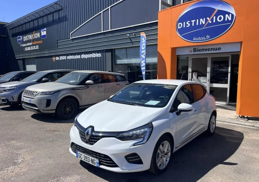 Renault Clio blanc Quartz vue 3/4 avant droit, garée devant un concessionnaire Distinxion.