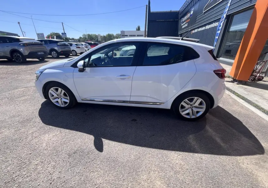 Renault Clio blanc Quartz vue de profil côté gauche sur parking ensoleillé avec jantes alliage.