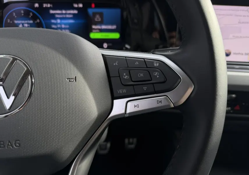Gros plan sur le volant multifonction cuir de la Volkswagen Golf 8 gris lunaire avec commandes et affichage numérique en arrière-plan.