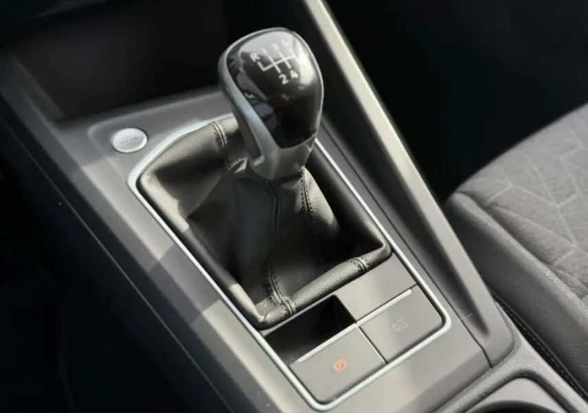 Gros plan sur le levier de vitesses manuel noir et gris dans la console centrale de la Volkswagen Golf 8 gris lunaire.