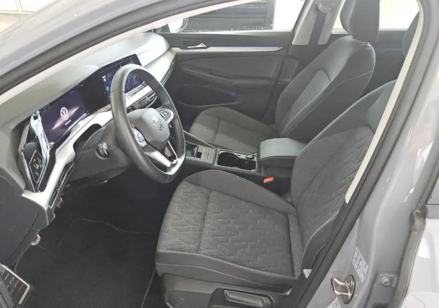 Intérieur avant droit de la Volkswagen Golf 8 gris lunaire, sièges tissu et tableau de bord digital moderne.