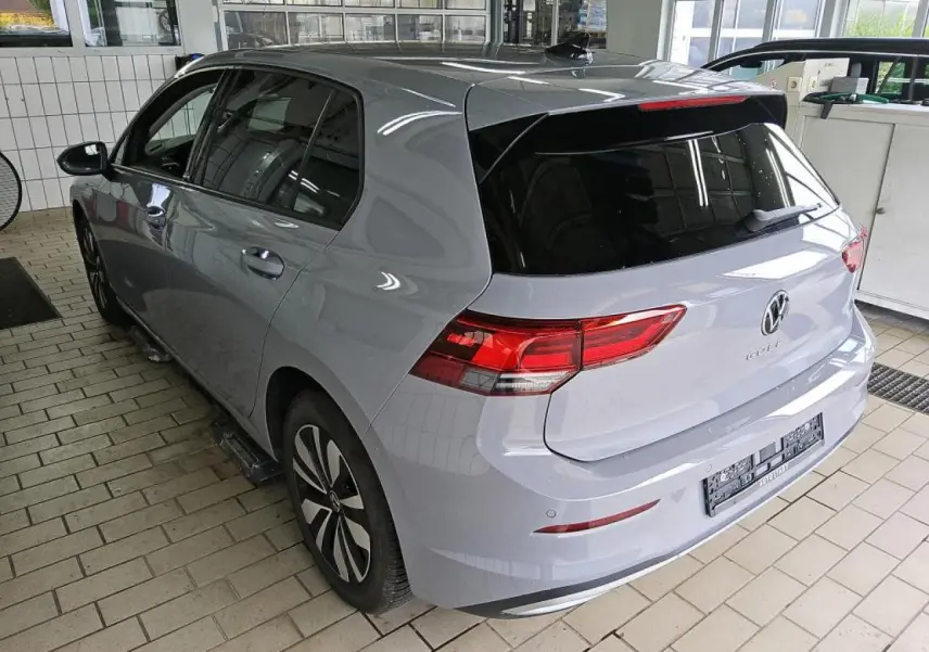 Volkswagen Golf 8 gris lunaire vue 3/4 arrière droit, feux arrière LED et vitres teintées dans un garage.