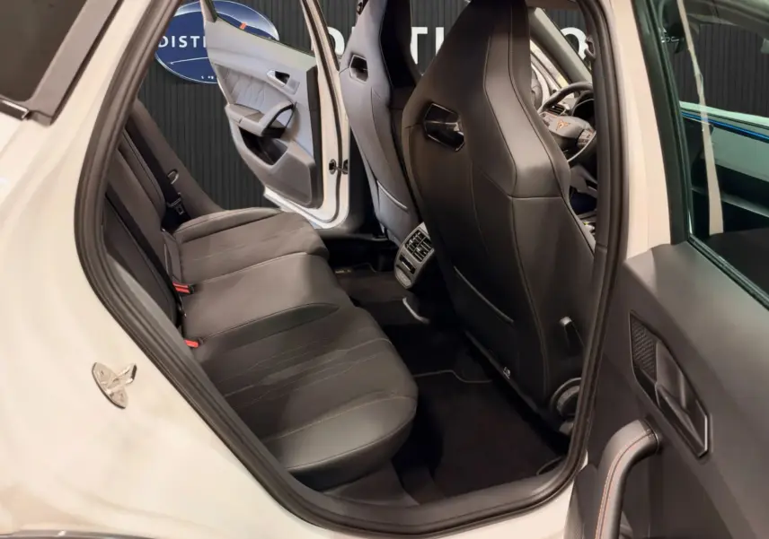 Vue intérieure arrière droite d'une CUPRA Formentor blanche 2024, sièges en cuir noir et détails orange sur les coutures.