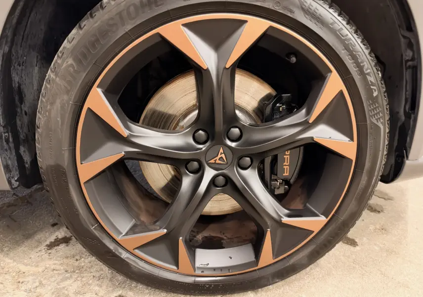 Gros plan sur la jante bicolore noire et cuivre avec logo CUPRA sur roue avant d’un CUPRA Formentor blanc 2024.