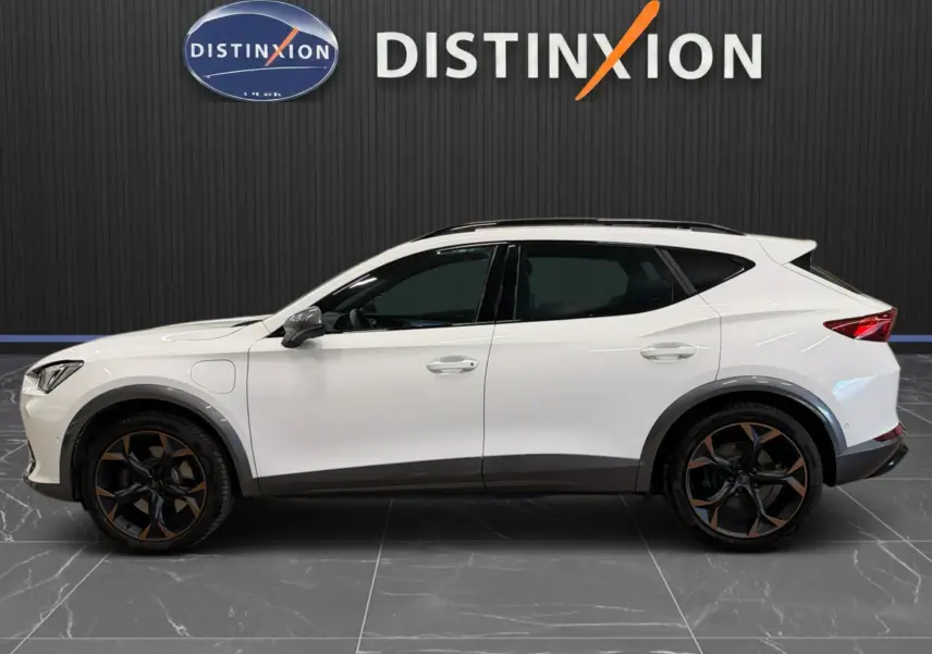 Vue de profil droit d'un CUPRA Formentor blanc 2024 avec jantes bi-ton noires et bronze, toit ouvrant et vitres teintées.