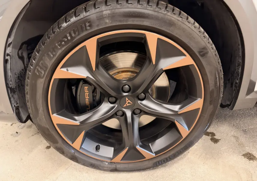 Gros plan sur la jante noire et cuivre avec logo CUPRA, montée sur pneu Bridgestone d'un CUPRA Formentor blanc.