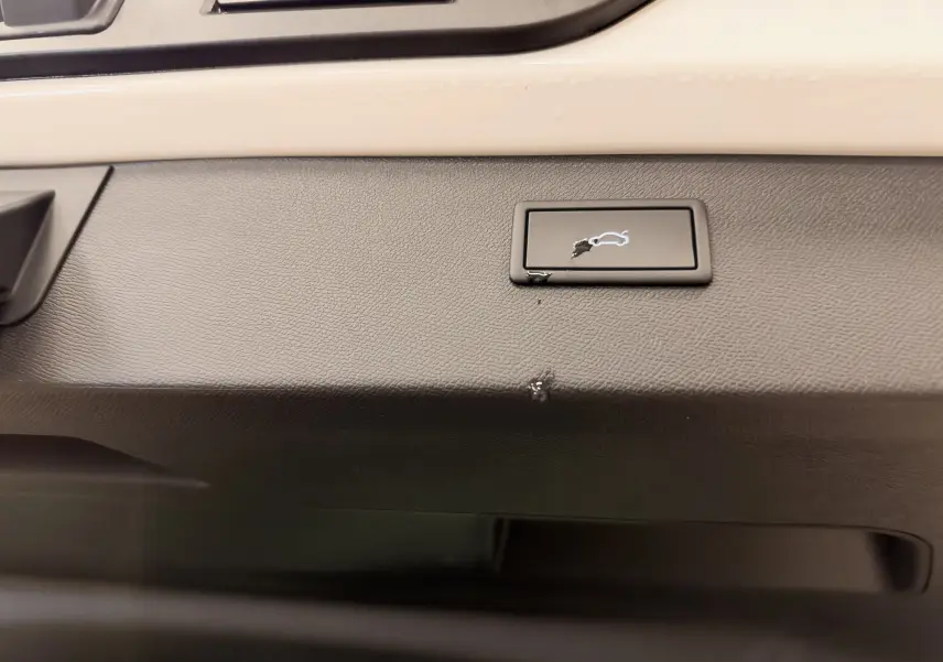 Bouton d'ouverture du coffre sur la garniture intérieure noire du hayon d'un CUPRA Formentor blanc.