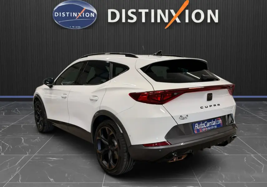 Vue 3/4 arrière droite d'un CUPRA Formentor blanc 2024 avec jantes noires et toit noir dans un showroom.