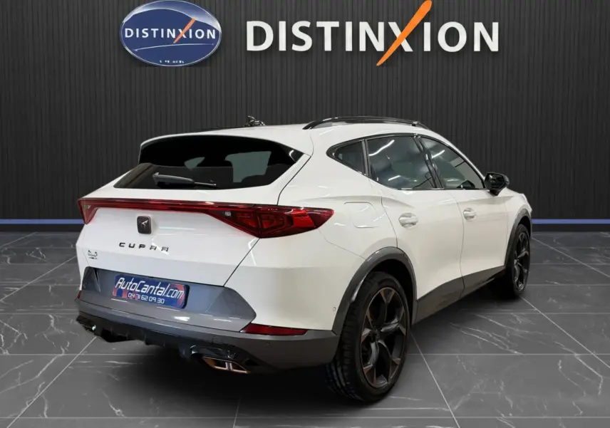 Vue 3/4 arrière droite d'une CUPRA Formentor blanche 2024 avec jantes noires et toit panoramique en showroom.