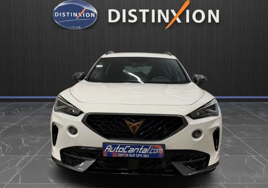 Vue de face du CUPRA Formentor blanc 2024 avec calandre noire et logo cuivré, dans un showroom au sol gris.