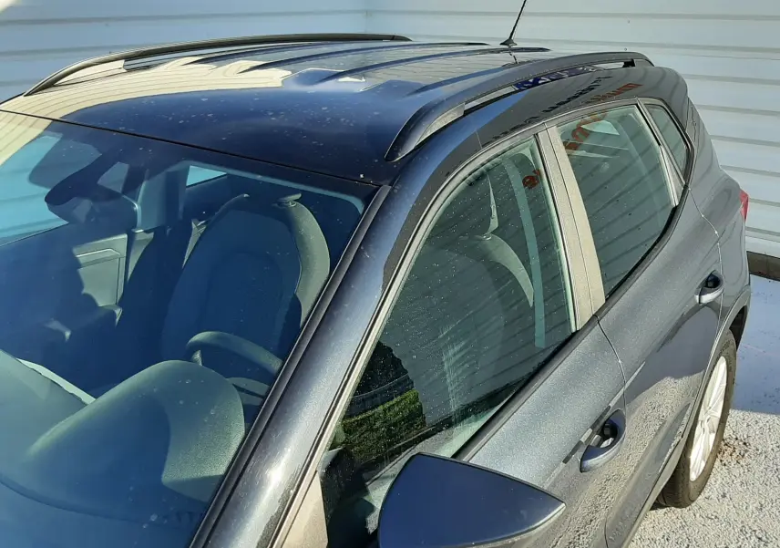 Vue de dessus côté droit d'un SEAT Arona gris magnetic avec toit noir et barres de toit visibles.