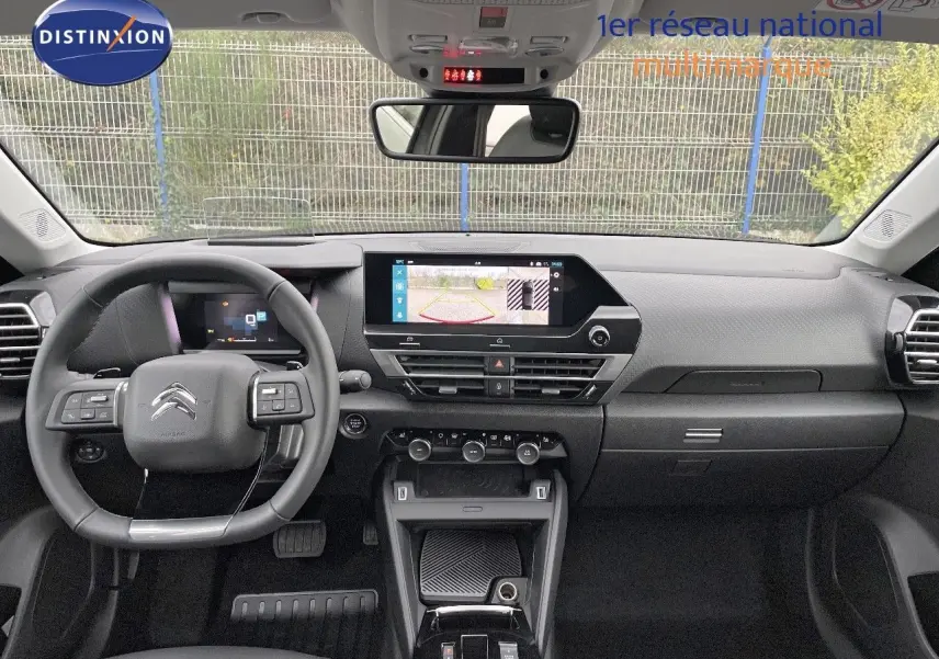 Vue intérieure avant du tableau de bord et volant noir de la Citroën C4 2024 avec écran tactile affichant la caméra de recul.
