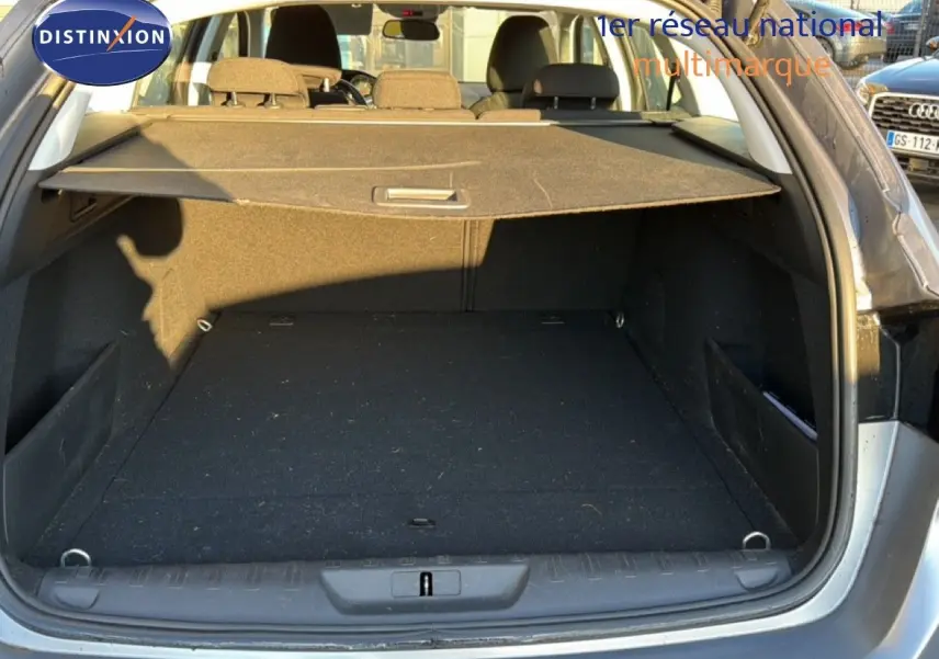 Coffre ouvert en vue arrière d'une Peugeot 308 SW gris Artense métal, montrant l'espace de chargement et la plage arrière.