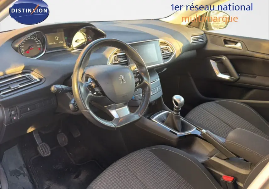 Intérieur avant droit de la Peugeot 308 SW 2019 avec volant cuir, tableau de bord numérique et sièges tissu noir.