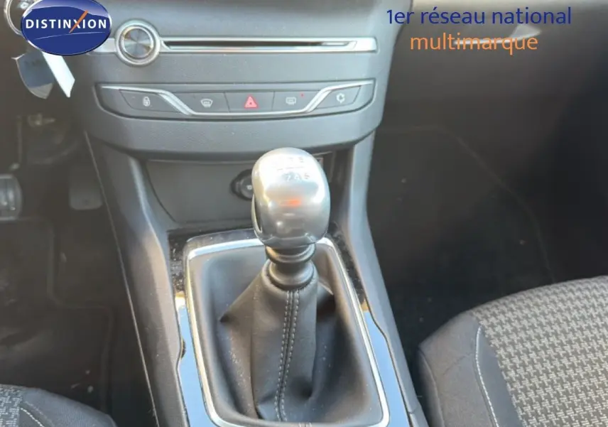 Le levier de vitesses manuel de la Peugeot 308 SW 2019 en gros plan, avec console centrale noire et sièges tissu gris.