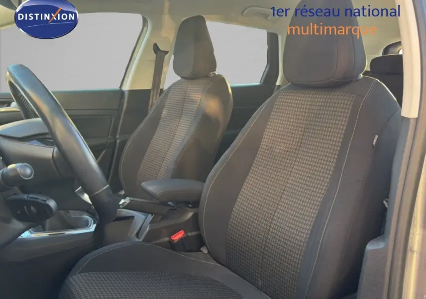 Vue intérieure côté conducteur de la Peugeot 308 SW 2019 avec sièges tissu noir à motifs et volant visible.