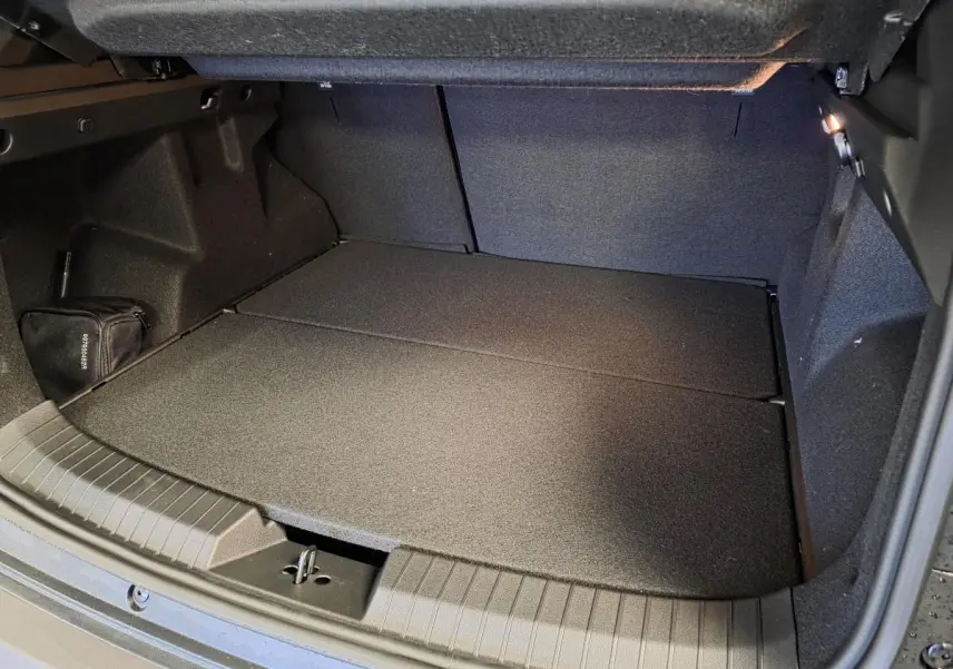 Coffre ouvert du Dacia Duster 1.6 Hybrid noir, montrant un espace de chargement plat et éclairé.