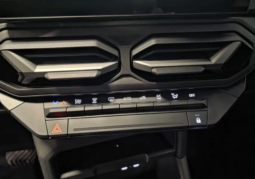 Vue rapprochée de la console centrale du Dacia Duster 2025, montrant les aérateurs gris acier et les commandes climatisation.