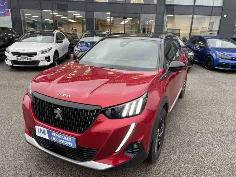 Peugeot 2008 130 GT-LINE rouge métal vue 3/4 avant, avec calandre noire et feux LED distinctifs allumés.