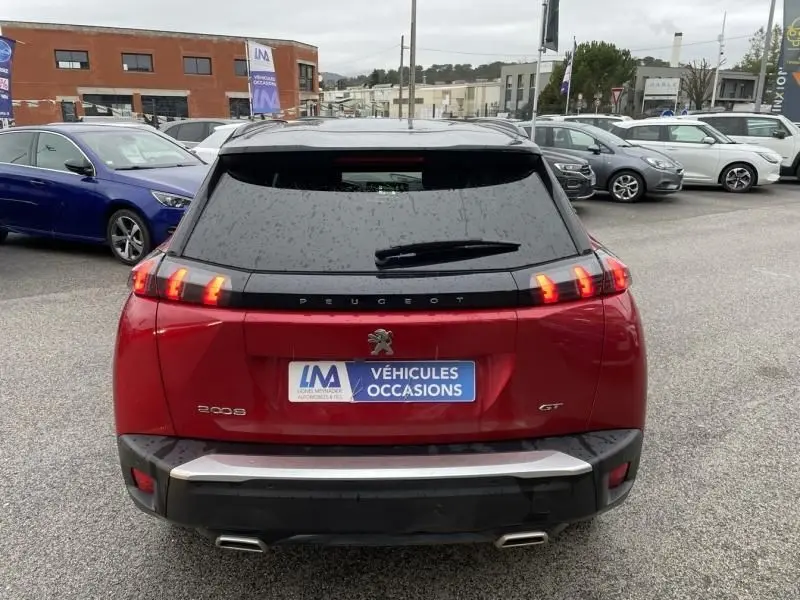 Vue arrière d’un Peugeot 2008 GT-LINE rouge métal 2022 avec feux LED caractéristiques et double sortie d’échappement.