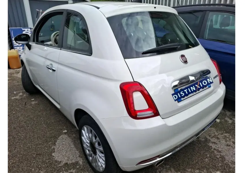 Vue 3/4 arrière droite d'une FIAT 500 blanche Bossa Nova, avec feux arrière rouges et jantes alliage multibranches.