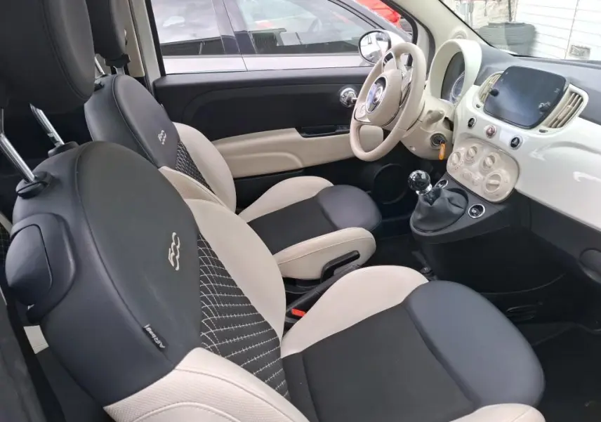 Vue intérieure côté conducteur de la FIAT 500 Dolcevita 2022 avec sièges bicolores noir et beige et tableau de bord blanc.