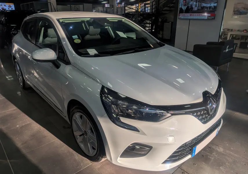 Renault Clio V Blue dCi 85 Business blanc glacier vue 3/4 avant droit en intérieur showroom.