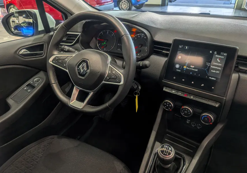 Vue intérieure côté conducteur de la Renault Clio V Business 2021, volant multifonction, écran tactile et levier de vitesse manuel.