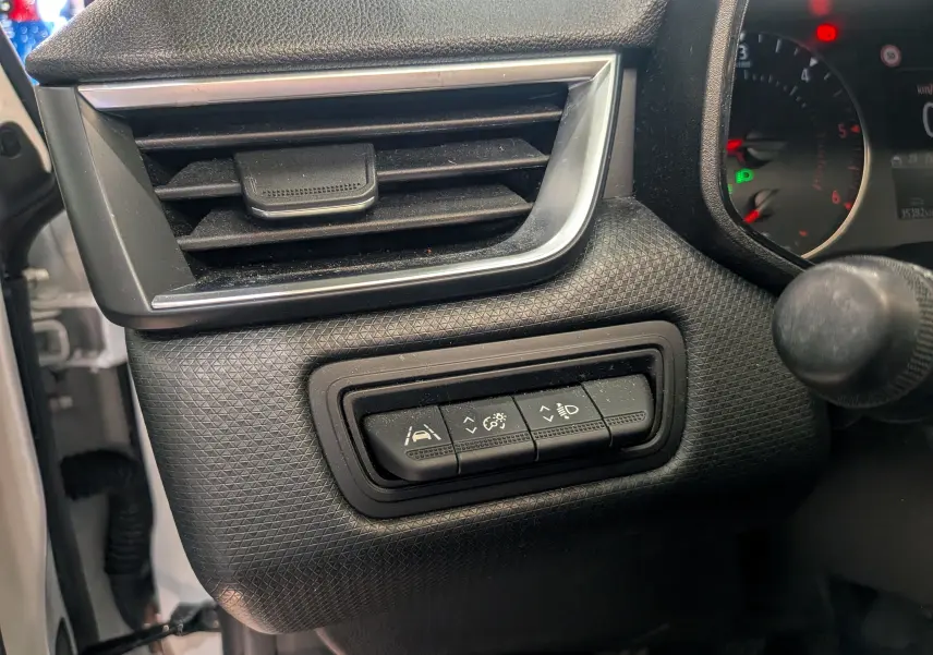 Détail intérieur du tableau de bord côté gauche de la Renault Clio V blanc glacier, avec commandes d'assistance et ventilation.