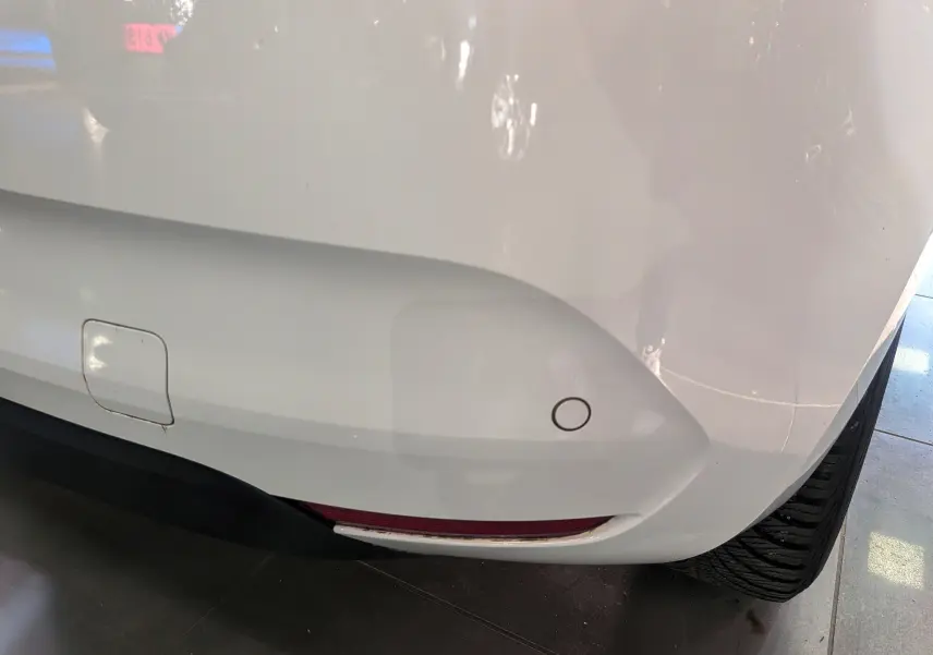Gros plan sur le coin arrière droit blanc glacier d'une Renault Clio V 2021, avec capteur de recul et feu antibrouillard.