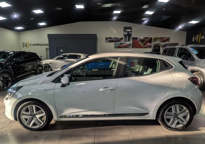 Profil droit d'une Renault Clio V Blanc Glacier 2021 en intérieur, avec jantes alliage et logo latéral Clio.