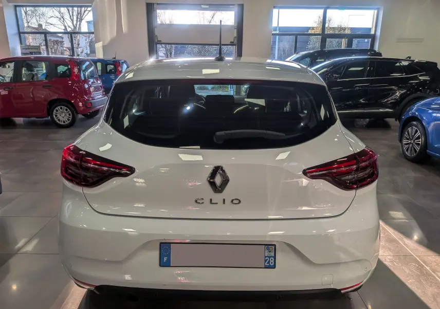 Vue arrière d'une Renault Clio V Blanc Glacier 2021 en showroom, avec feux arrière LED et logo central visible.