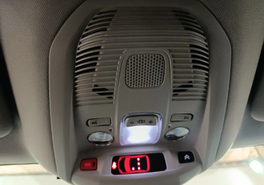 Vue intérieure du plafonnier gris avec éclairage, boutons SOS et commande d'ouverture du toit ouvrant du Citroën C5 Aircross blanc.