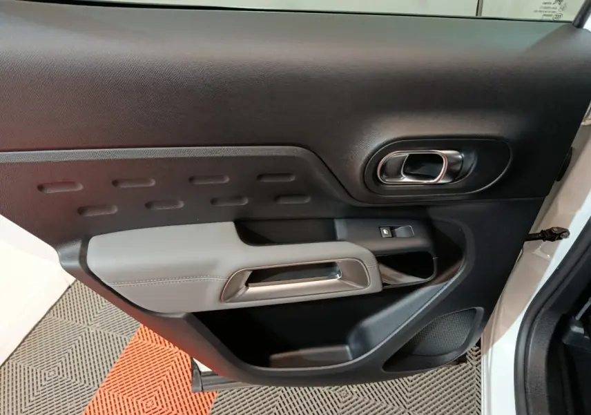 Vue rapprochée de la porte avant gauche blanche du Citroën C5 Aircross Hybrid, avec poignée intérieure grise et noire.