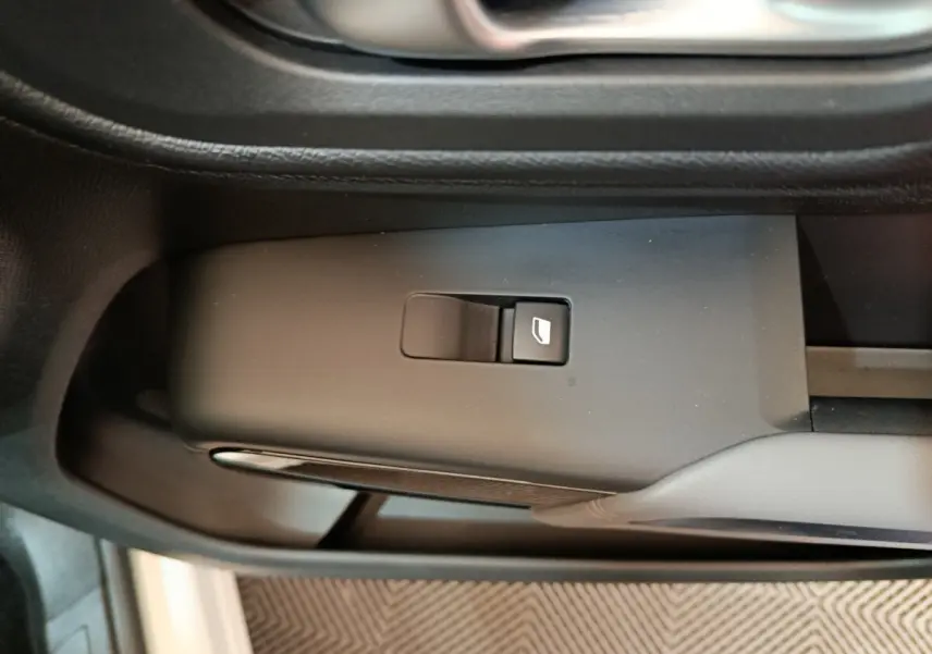 Gros plan sur le bouton de commande de vitre électrique côté conducteur dans l'intérieur noir du Citroën C5 Aircross blanc hybride.