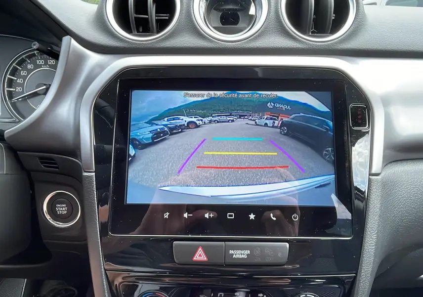 Vue intérieure centrée sur l'écran multimédia affichant la caméra de recul du Suzuki Vitara 2025, tableau de bord noir.