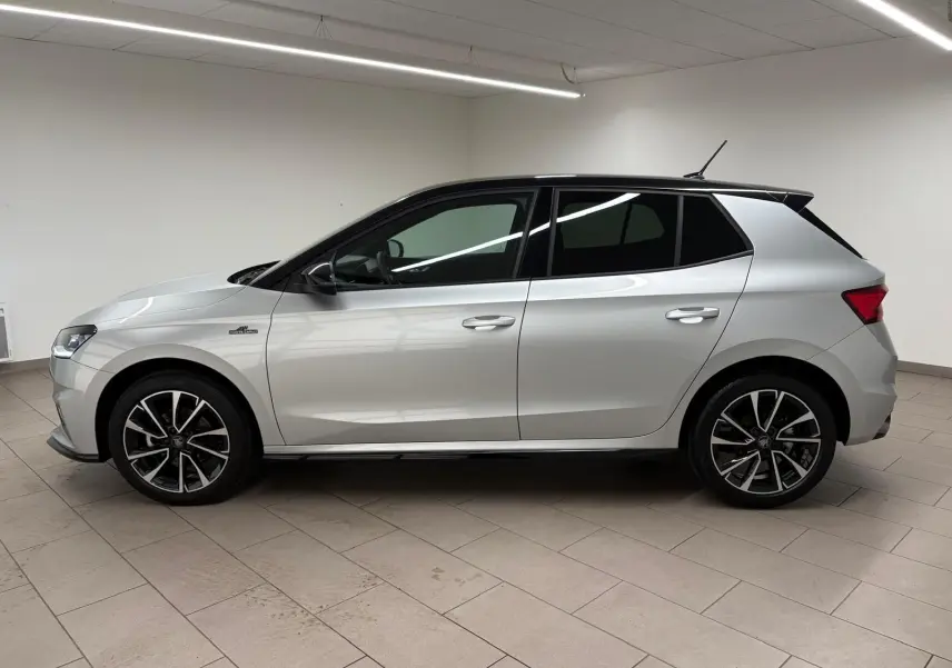 Vue de profil côté gauche d'une Skoda Fabia 2025 gris argent avec toit noir et jantes alliage noires.