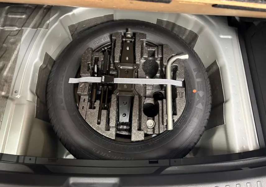 Gros plan sur la roue de secours et les outils de bord dans le coffre d'une Skoda Fabia 1.0 TSI 116 DSG7 Monte Carlo 2025.