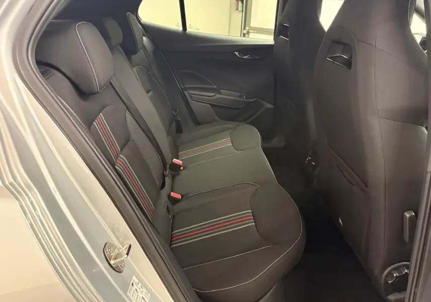 Vue intérieure arrière côté gauche de la Skoda Fabia 2025, sièges noirs avec bandes rouges et coutures blanches.