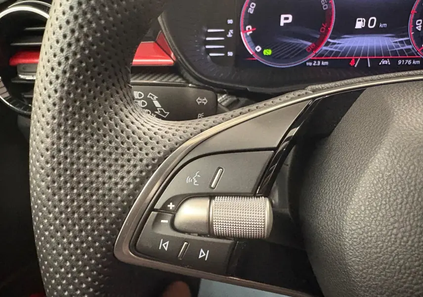 Gros plan sur la partie gauche du volant perforé de la Skoda Fabia 2025 avec commandes audio et tableau de bord numérique.