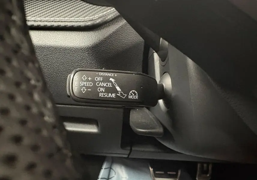 Gros plan sur la commande du régulateur de vitesse adaptatif dans une Skoda Fabia 2025, intérieur noir.