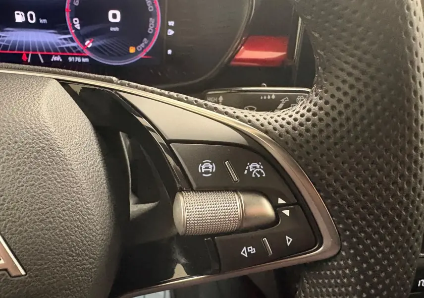 Gros plan sur les commandes au volant perforé de la Skoda Fabia 1.0 TSI 116 DSG7 Monte Carlo, tableau de bord numérique visible.