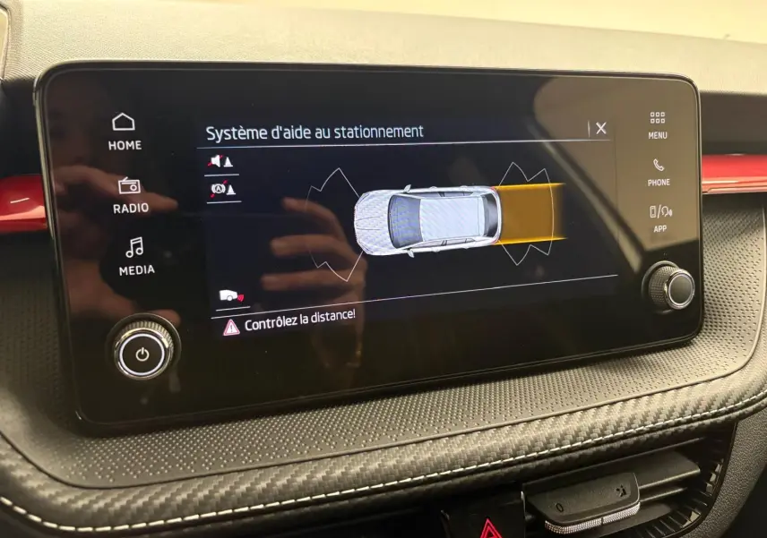 Écran tactile du système d'aide au stationnement dans une Skoda Fabia 2025, tableau de bord noir avec surpiqûres blanches.