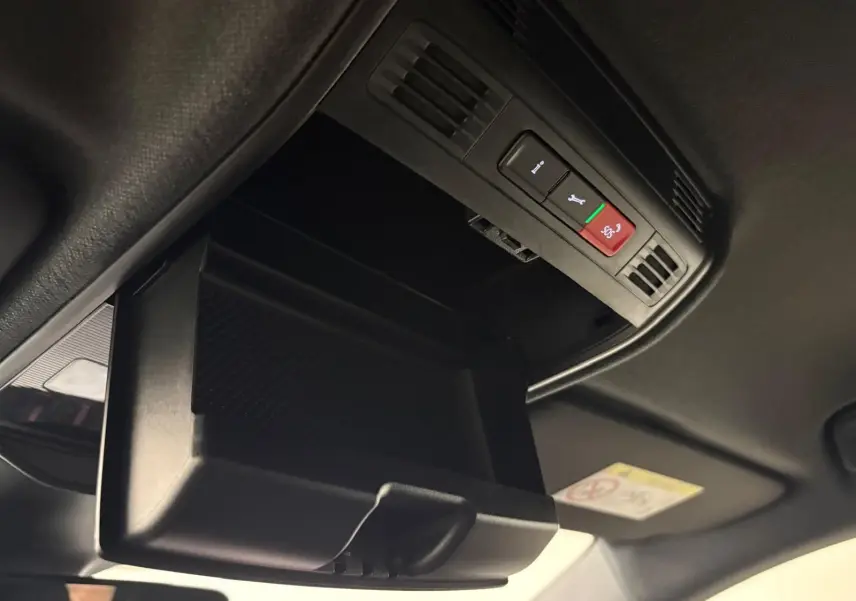 Gros plan sur le rangement plafond ouvert avec boutons SOS et assistance dans l’habitacle noir de la Skoda Fabia 2025.