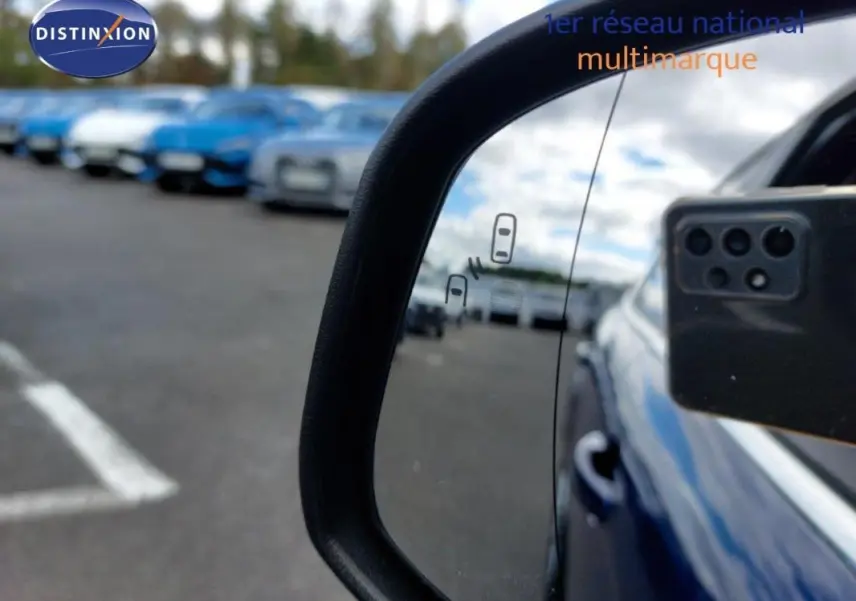 Rétroviseur droit d’une Ford Focus SW bleu foncé, avec plusieurs véhicules flous en arrière-plan.