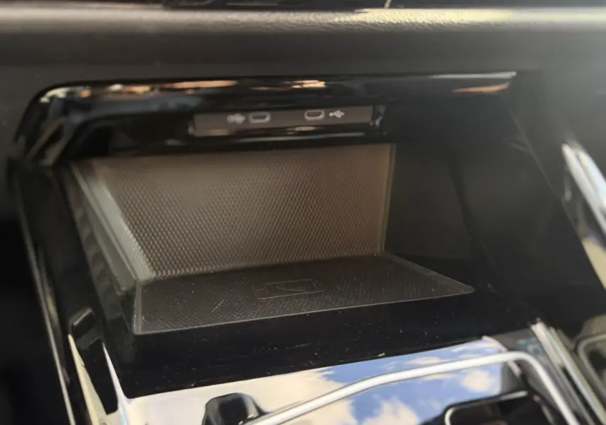 Gros plan sur la console centrale noire de la Volkswagen Golf 8 avec espace de rangement et ports USB visibles.