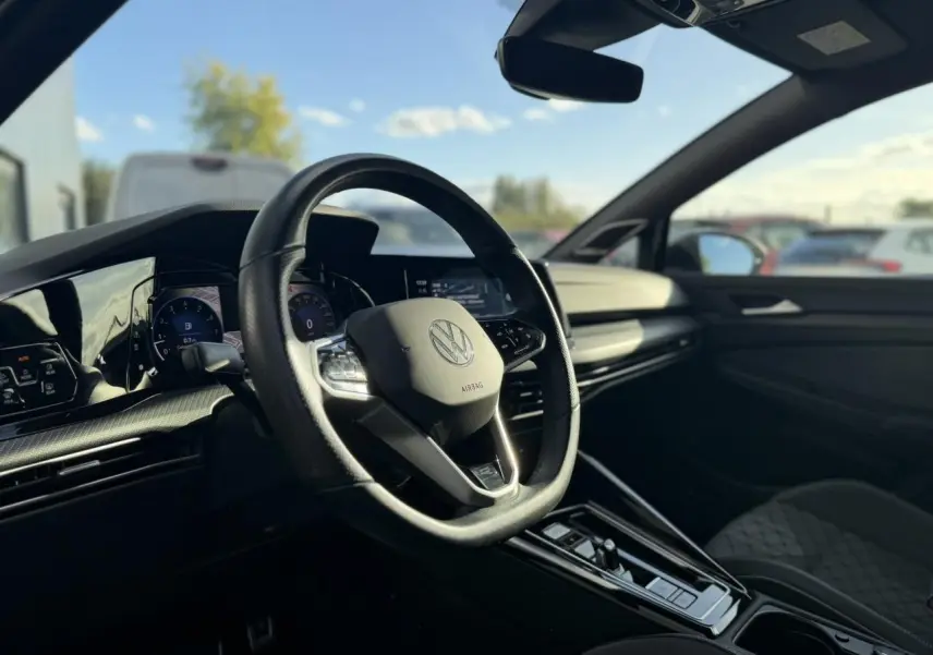 Vue intérieure côté conducteur de la Volkswagen Golf 8 R-Line 2024, avec volant cuir multifonction et tableau de bord digital.