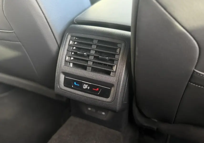 Détail de la console arrière noire avec diffuseurs d'air et commandes de chauffage des sièges dans une Volkswagen Golf 8 R-Line.