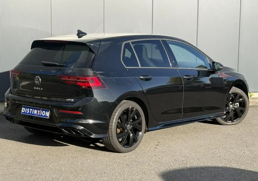 Volkswagen Golf 8 noir vue 3/4 arrière droit avec jantes noires et attelage escamotable visible.