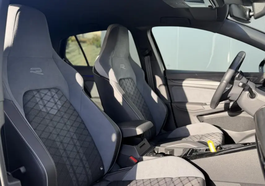 Vue intérieure côté gauche de la Volkswagen Golf 8 R-Line 2024 avec sièges sport gris à motifs et volant cuir noir.